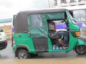 A bajaj, outfitted for the rainy season.  Usually the back, where the passengers sit, is open like the front.